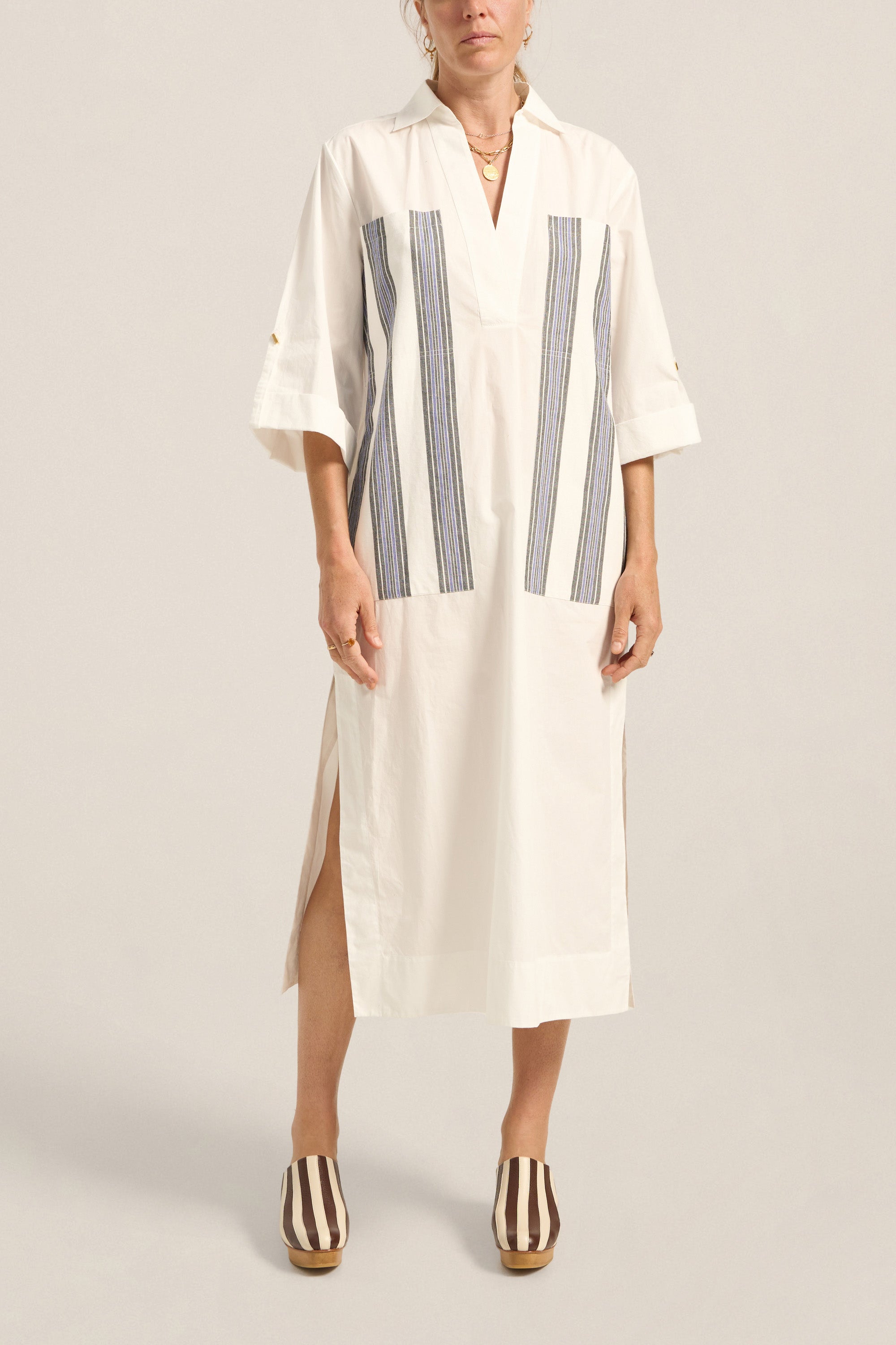 Woman wearing a white dress with blue stripes on a plain background