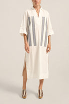 Woman wearing a white dress with blue stripes on a plain background