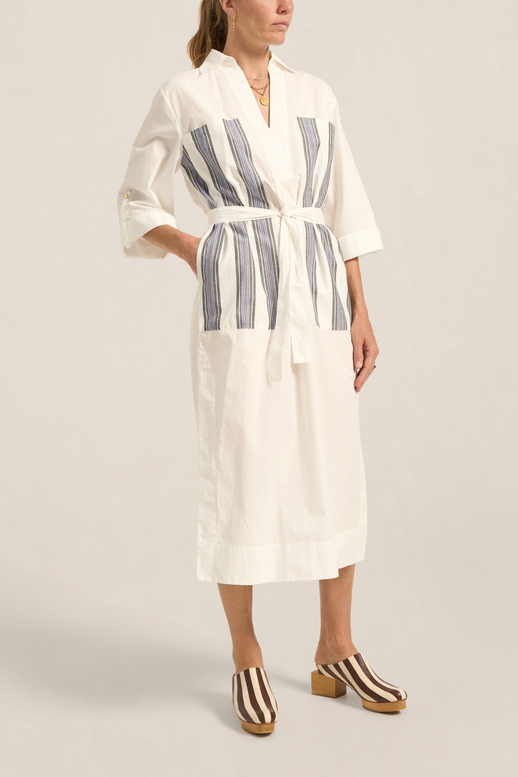 Woman wearing a white robe with blue stripes on a plain background