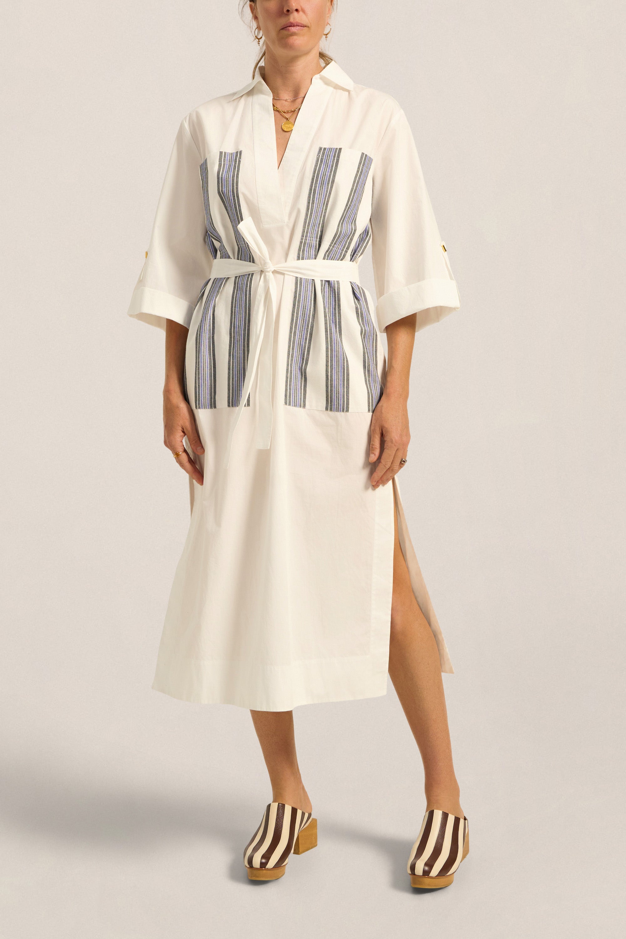 Woman wearing a white dress with blue stripes on a plain background