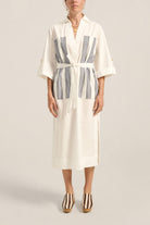 Woman wearing a white robe with blue stripes on a plain background