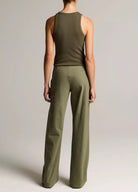 Person wearing a green tank top and wide-leg pants on a plain background