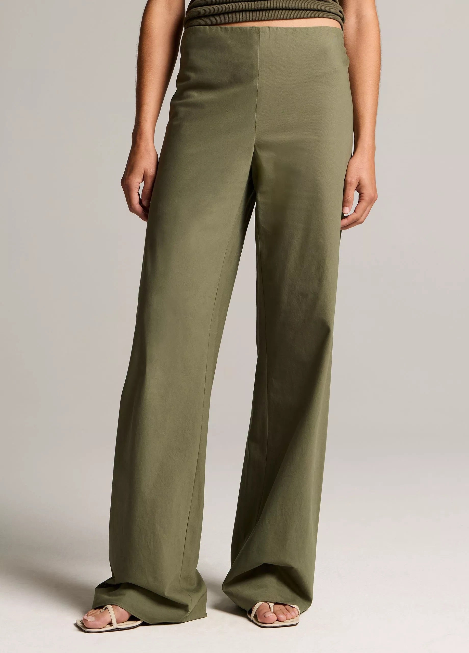 Person wearing olive green wide-leg pants on a plain background