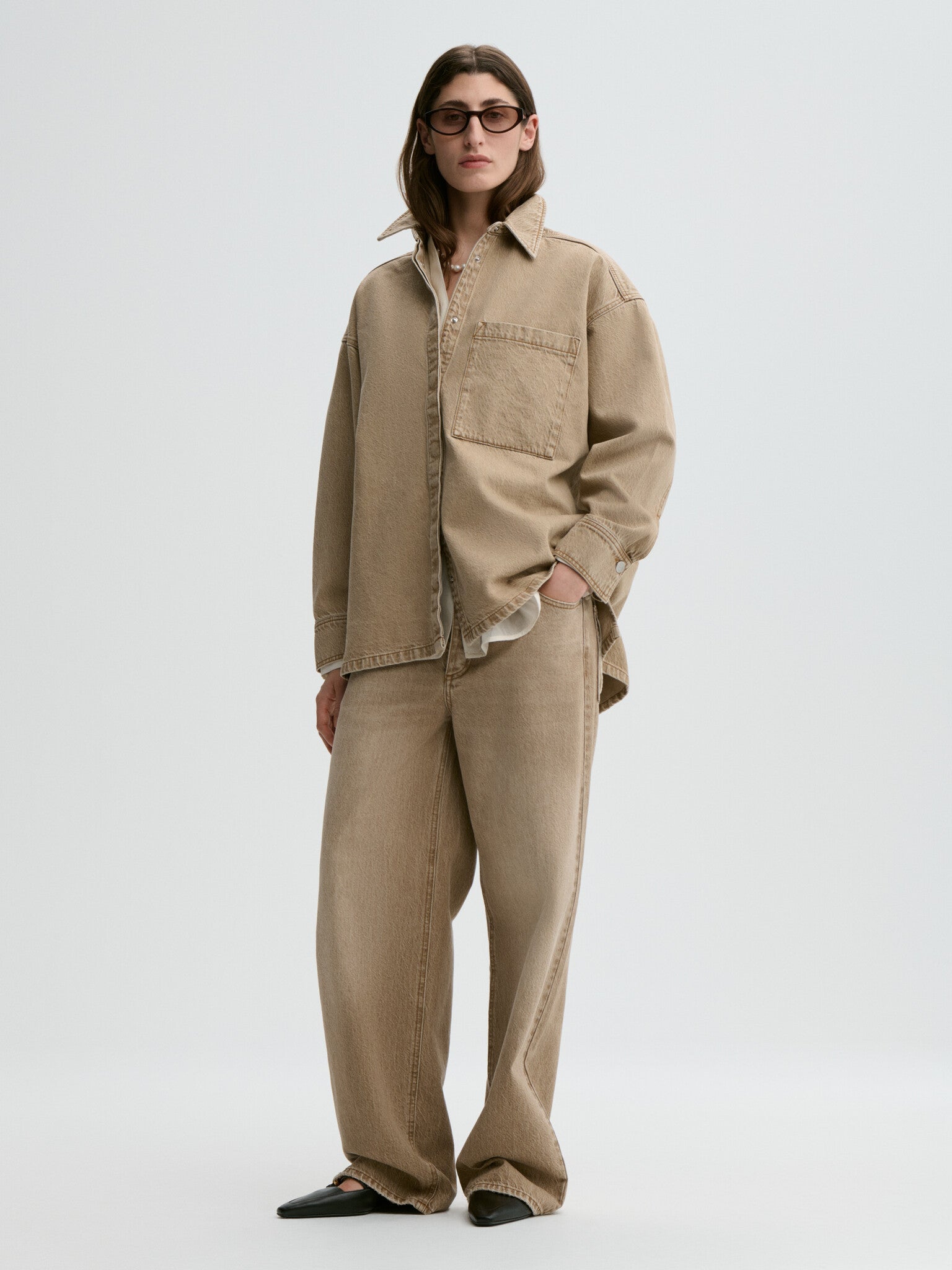 Person wearing a beige jacket and pants on a white background