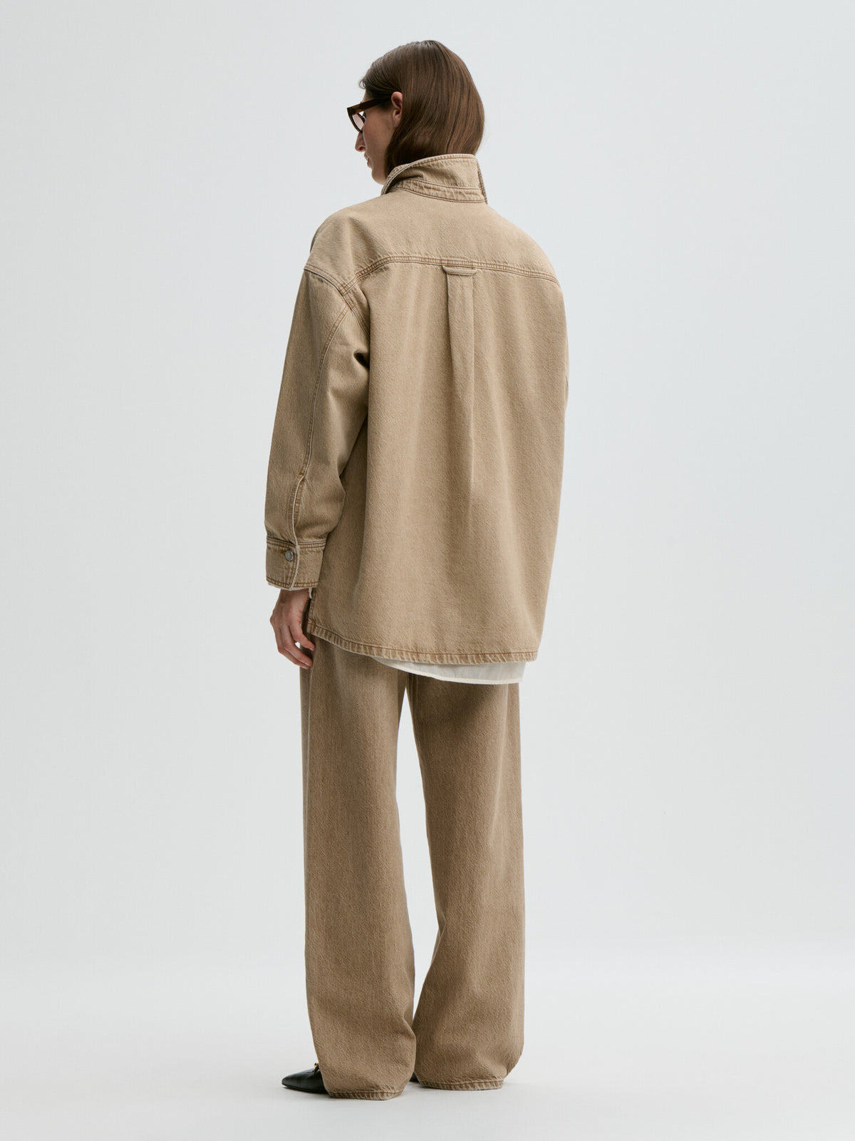 Person wearing a beige jacket and pants on a white background