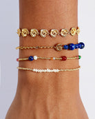 Multiple bracelets on a wrist against a neutral background