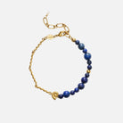 Gold bracelet with blue beads on a white background
