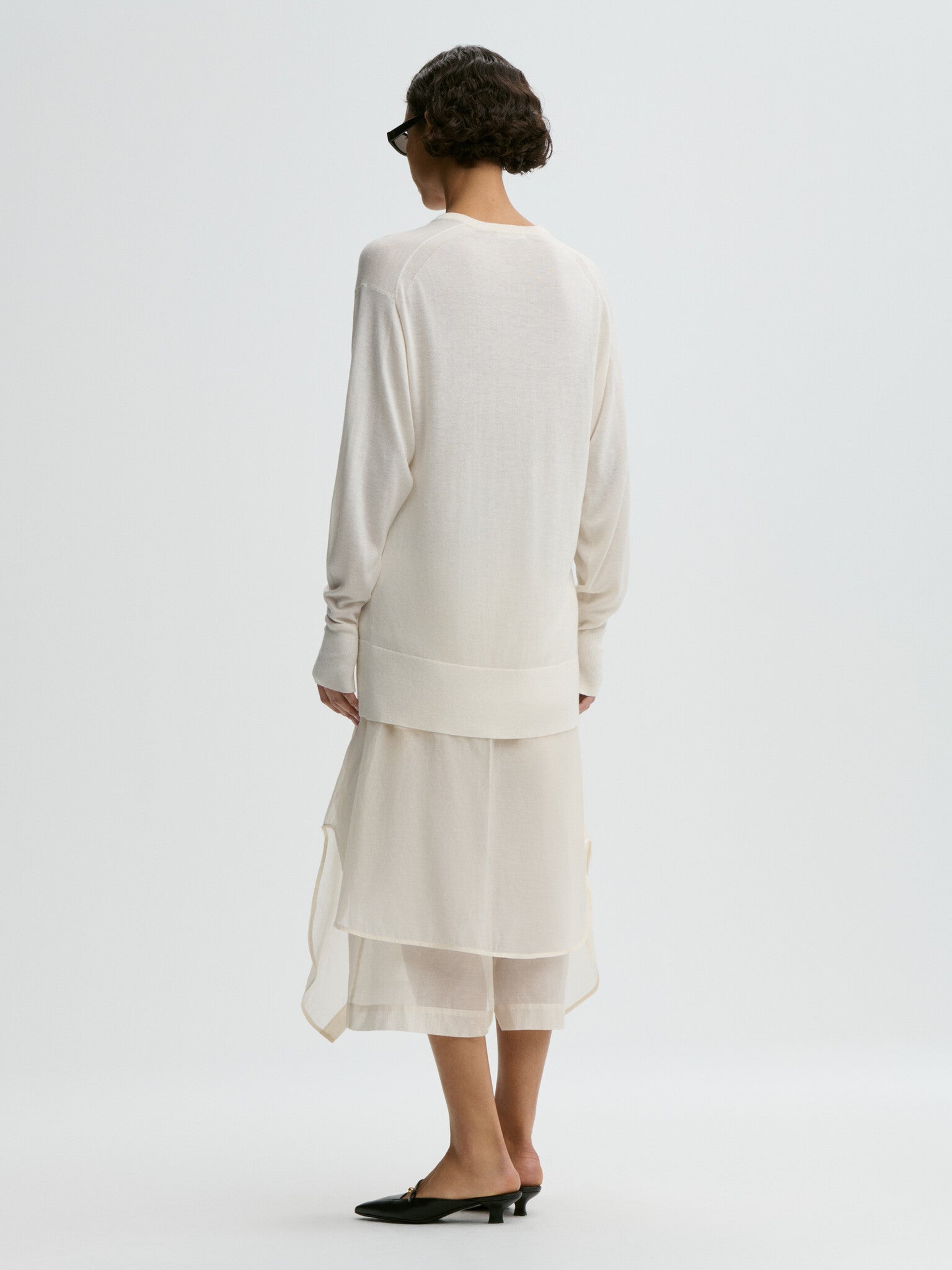 Woman wearing a white outfit on a plain background