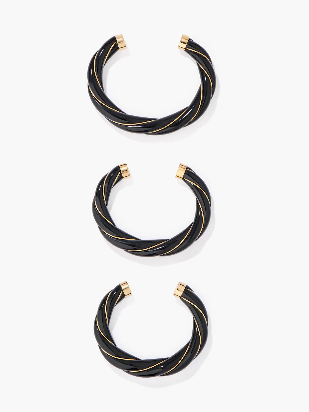 Set of black bangles with gold accents on a white background