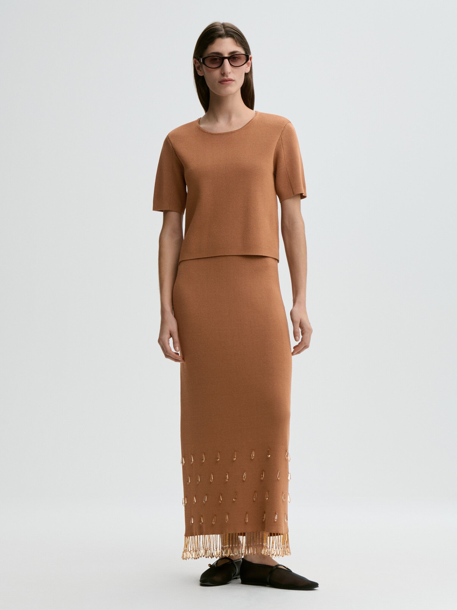 Woman wearing a brown outfit with a plain background