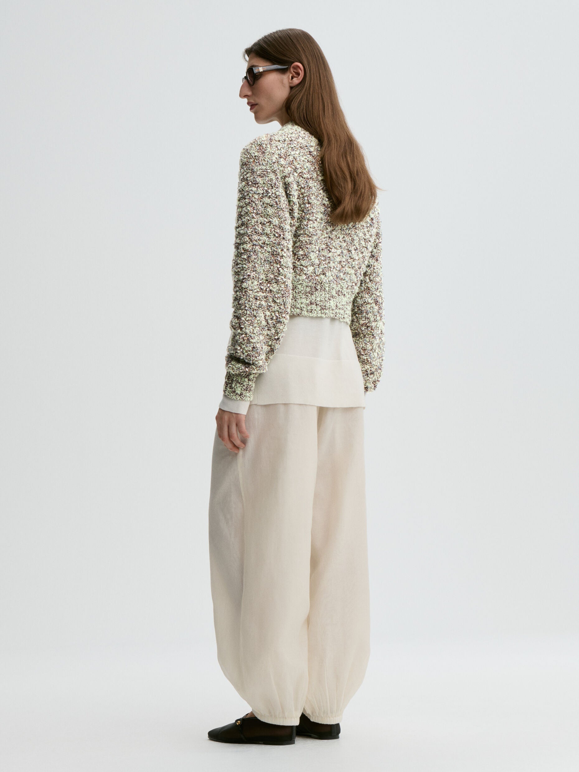 Woman wearing a textured sweater and wide-leg pants on a white background