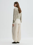 Woman wearing a textured sweater and wide-leg pants on a white background