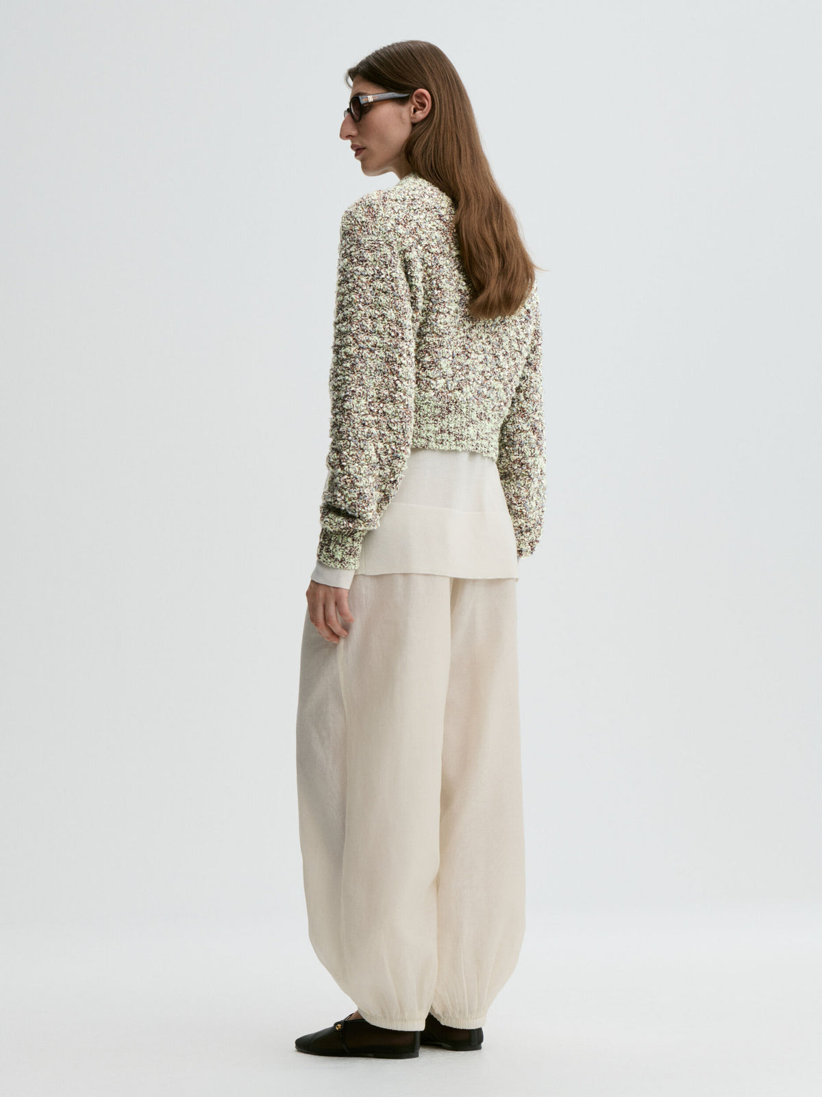 Woman wearing a textured sweater and wide-leg pants on a white background