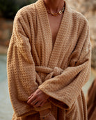 Person wearing a beige robe with a blurred natural background