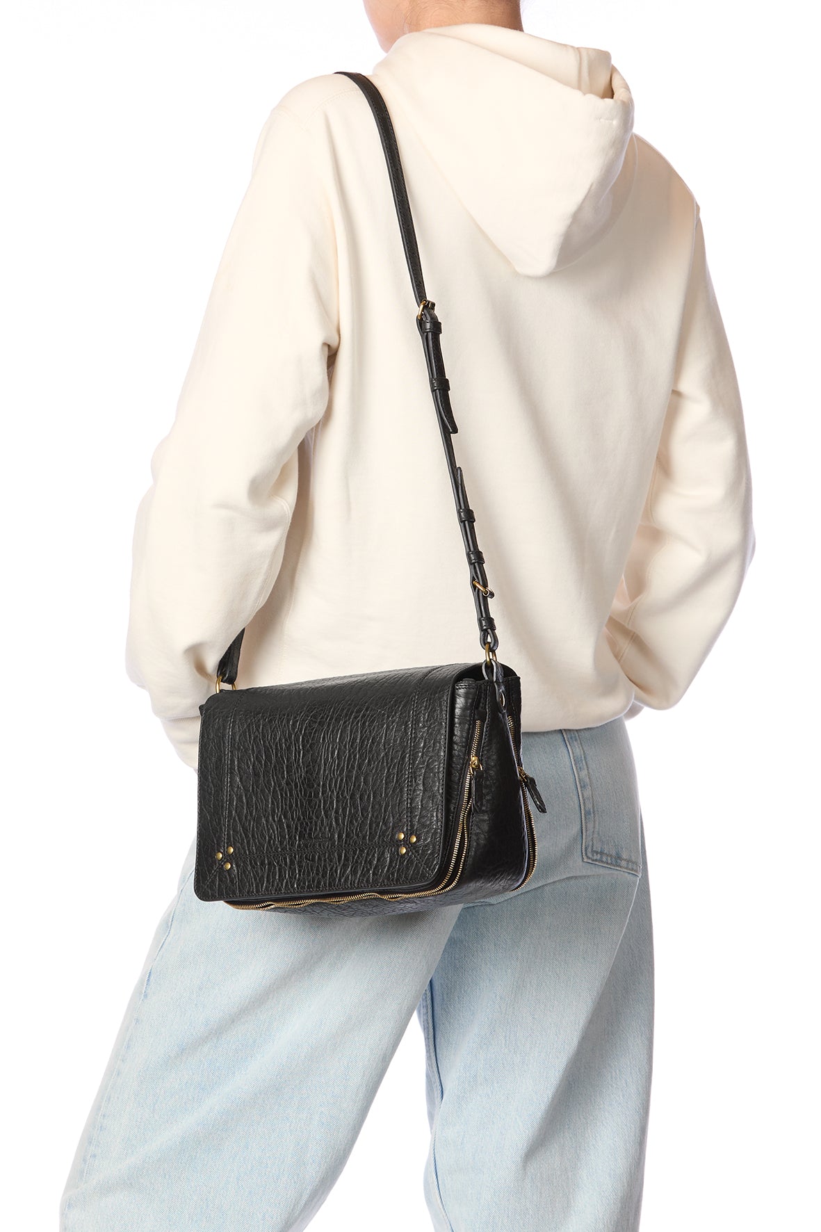 Person wearing a black leather crossbody bag with a white background