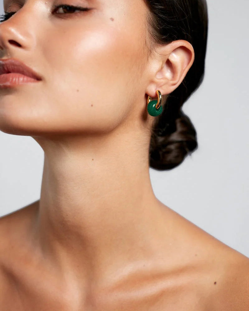 Close-up of a woman wearing green hoop earrings background