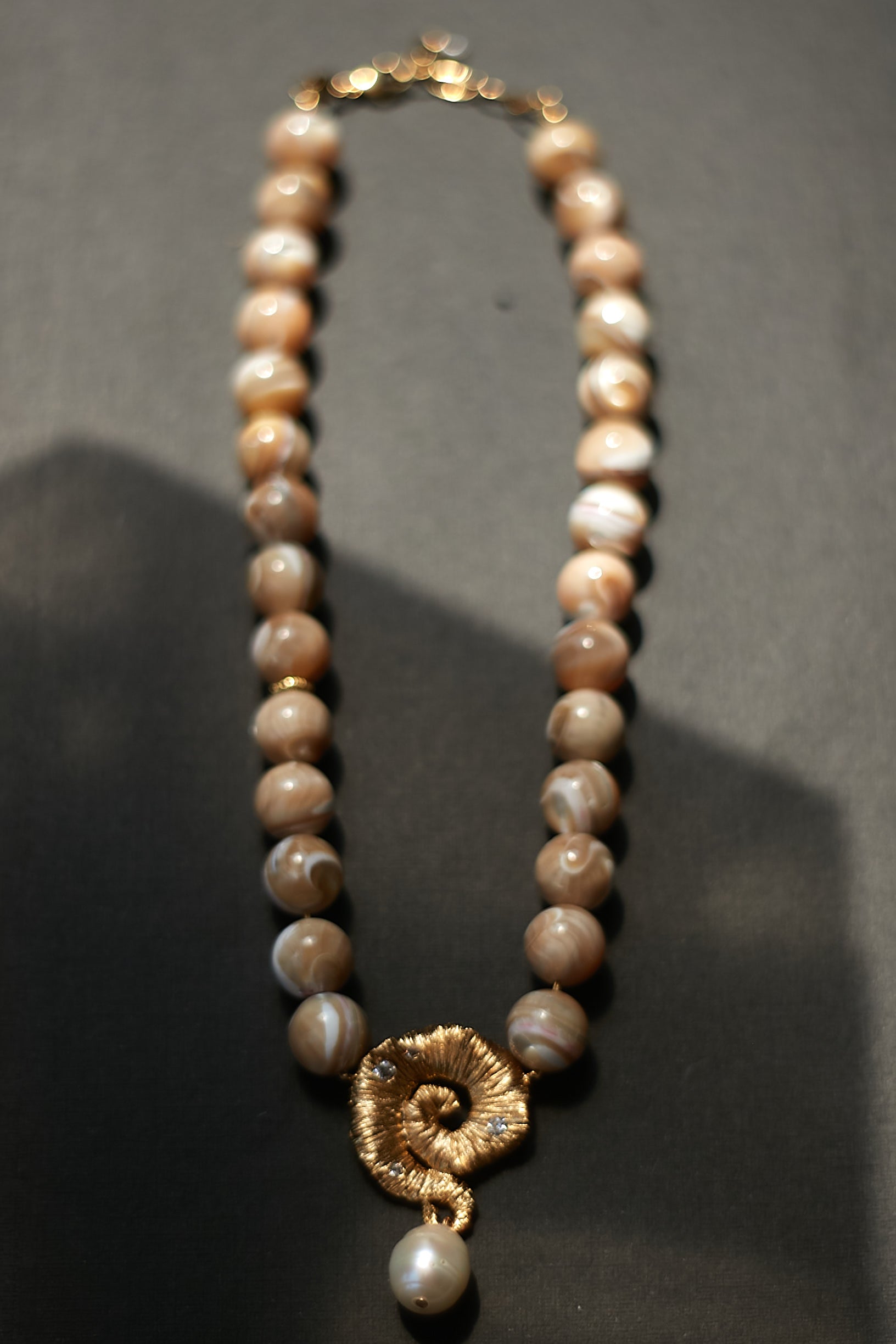 Pearl necklace with a gold clasp on a dark background
