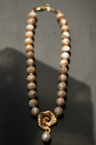 Pearl necklace with a gold clasp on a dark background