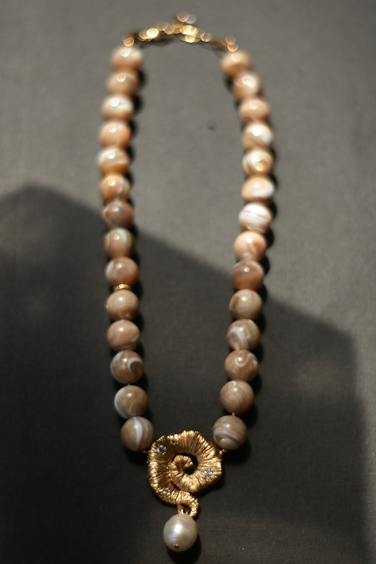 Pearl necklace with a gold clasp on a dark background