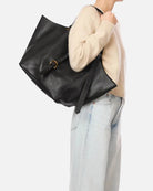 Person holding a black handbag with a visible brand logo on a white background