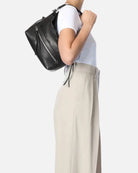 Person wearing a black backpack and beige pants on a white background