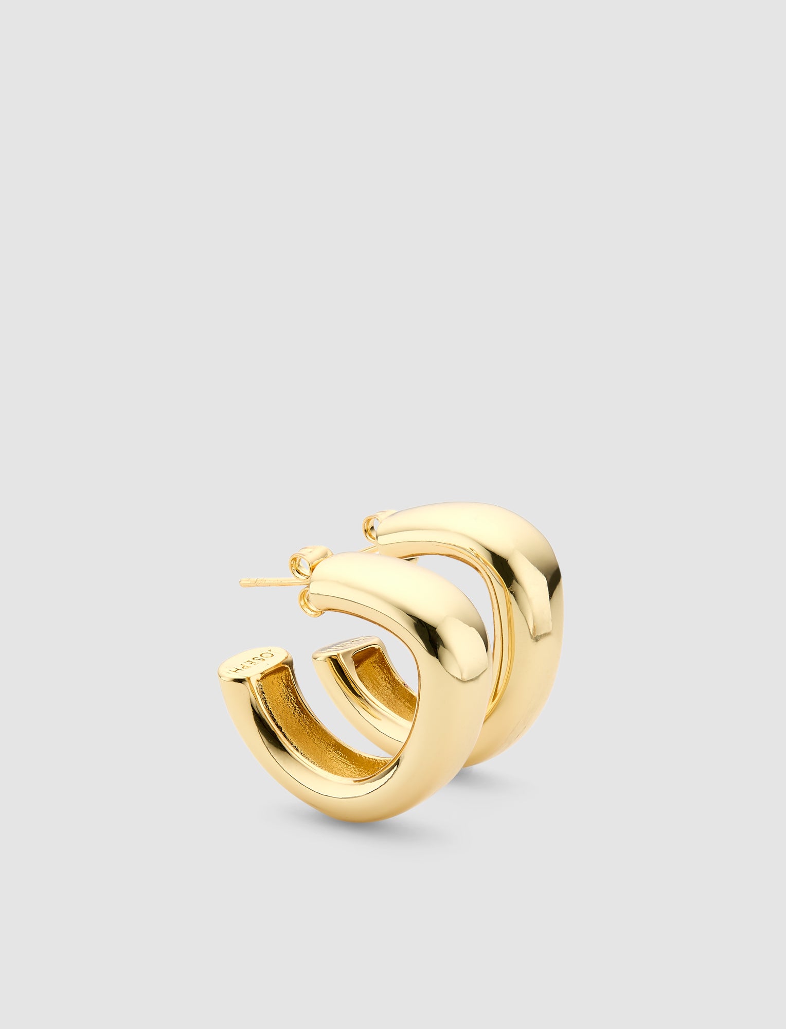 Gold hoop earring on a light gray background