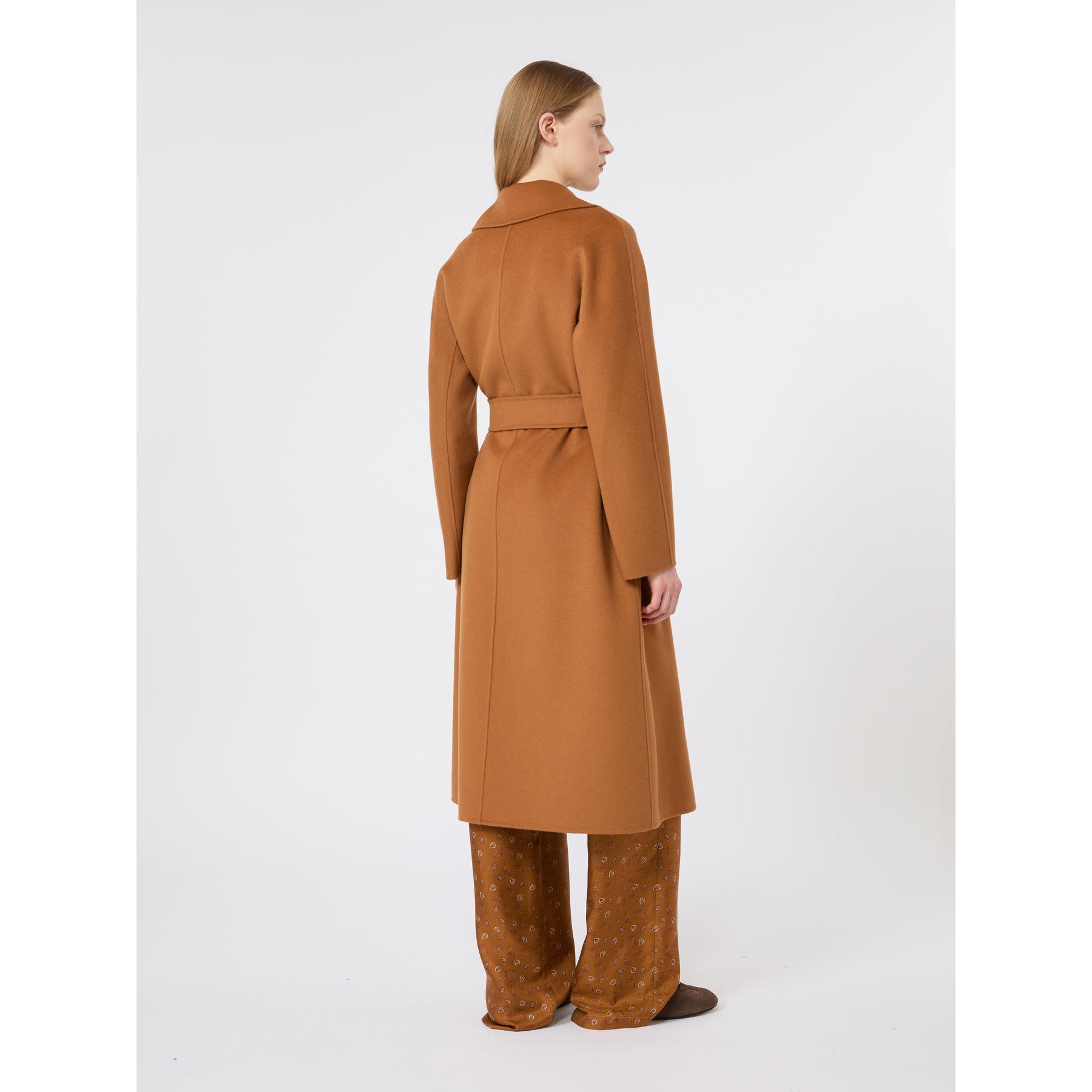 Woman wearing a brown coat and pants on a white background