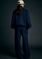 Person wearing a navy outfit with a white cap on a dark background