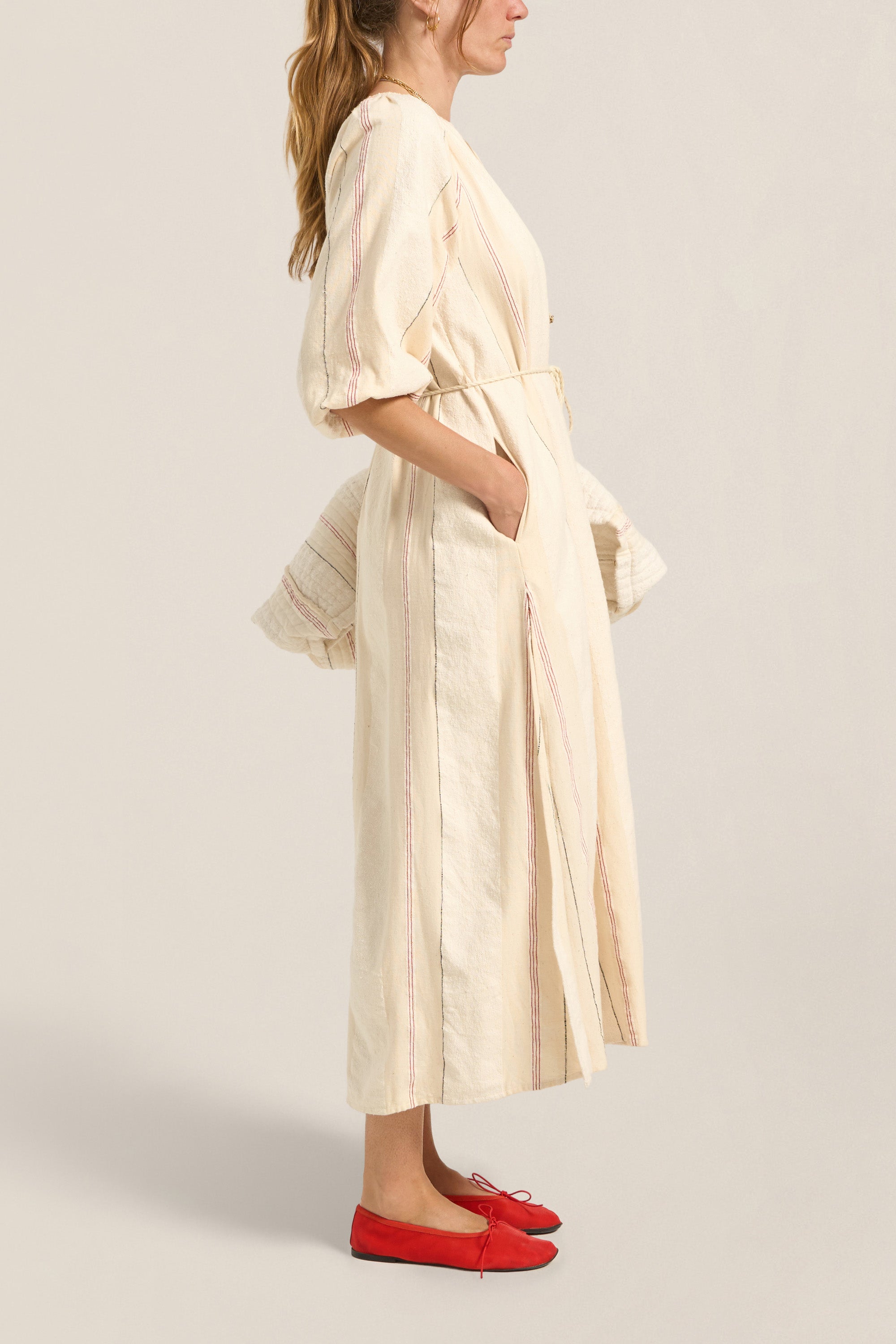 Woman wearing a long, light-colored dress with a plain background
