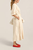 Woman wearing a long, light-colored dress with a plain background
