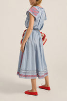 Woman wearing a light blue dress with red and white patterns on a beige background