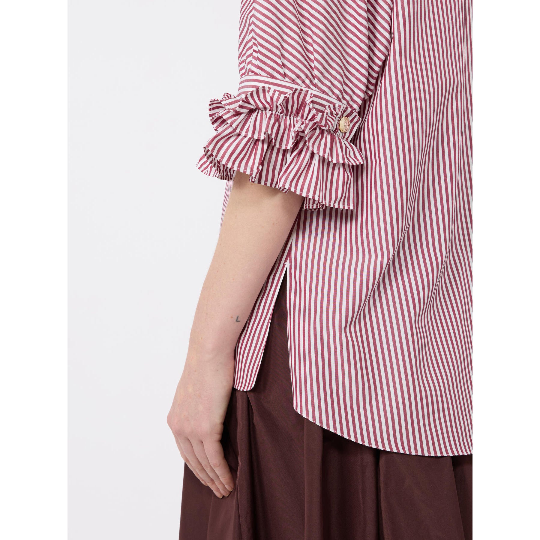 Red and white striped shirt with ruffled sleeves worn by a person on a white background