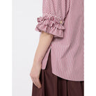 Red and white striped shirt with ruffled sleeves worn by a person on a white background