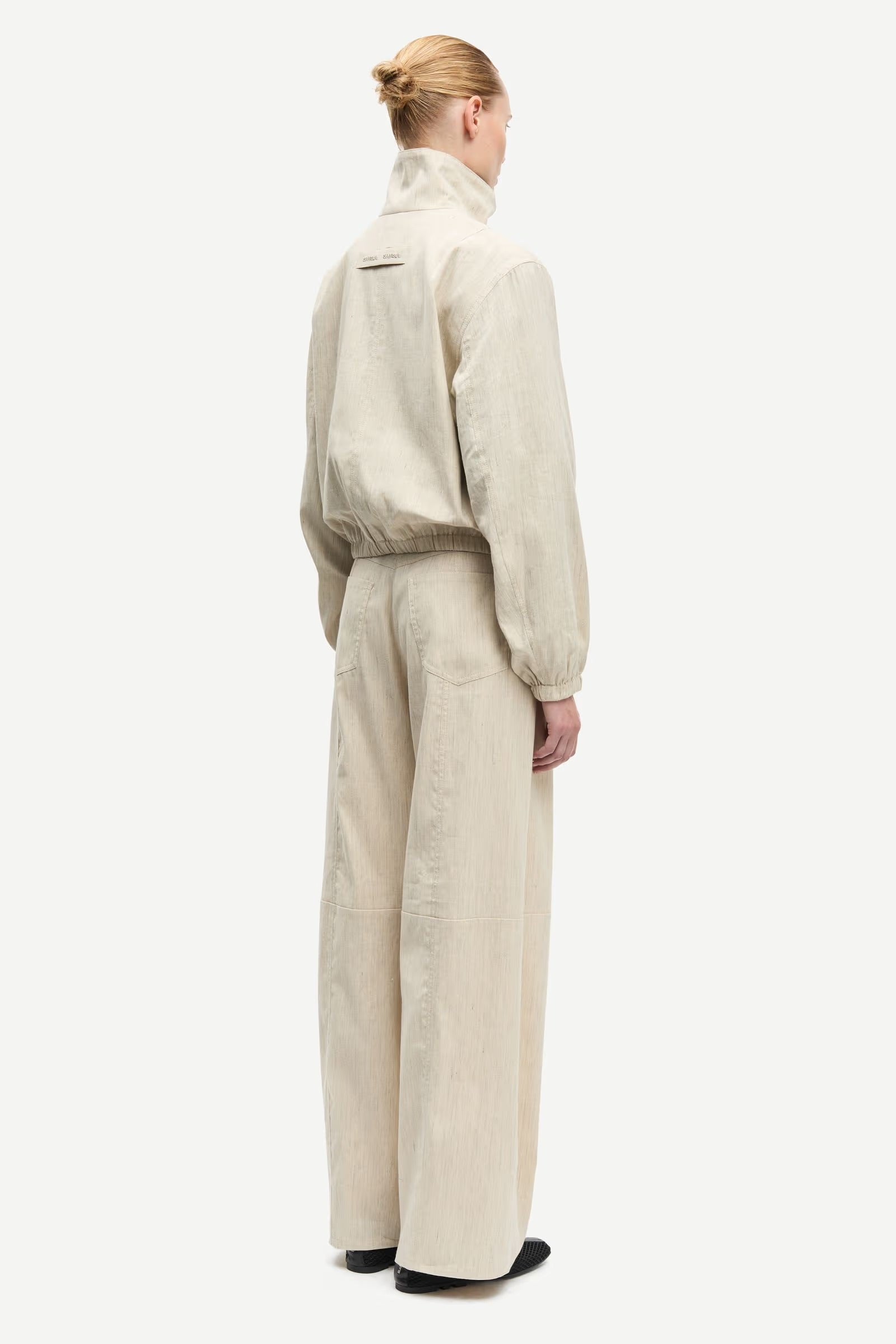 Person wearing a beige jumpsuit on a white background