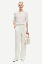 Woman wearing a white outfit with a plain background