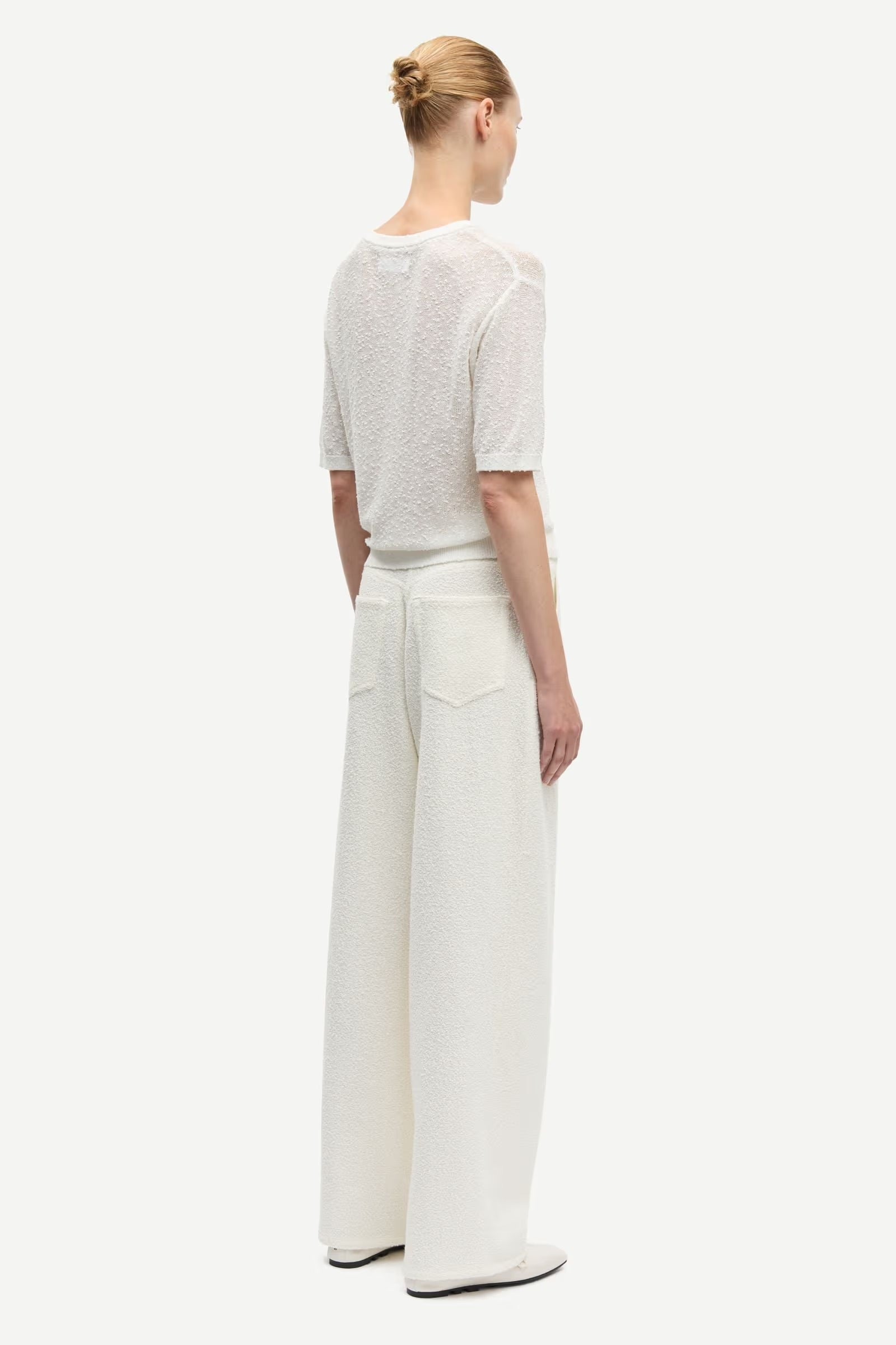 Person wearing a white top and wide-leg pants on a white background