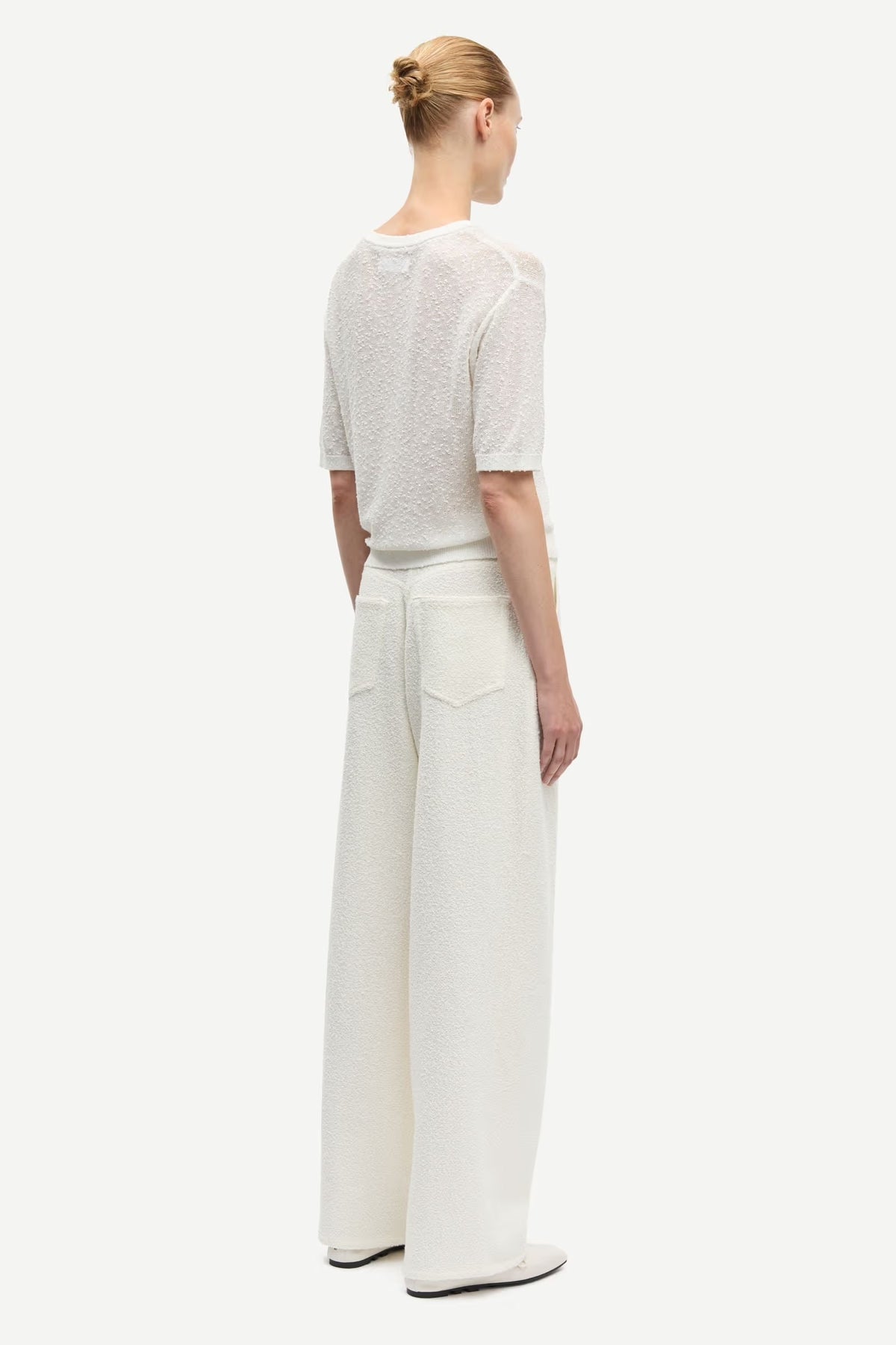 Person wearing a white top and wide-leg pants on a white background