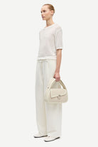 Woman holding a cream handbag against a white background