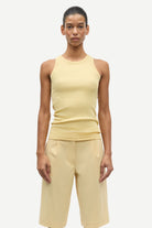 Person wearing a beige tank top and shorts on a white background