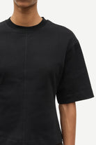 Black t-shirt worn by a person on a white background
