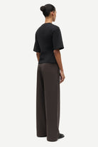 Person wearing a black top and dark pants on a white background
