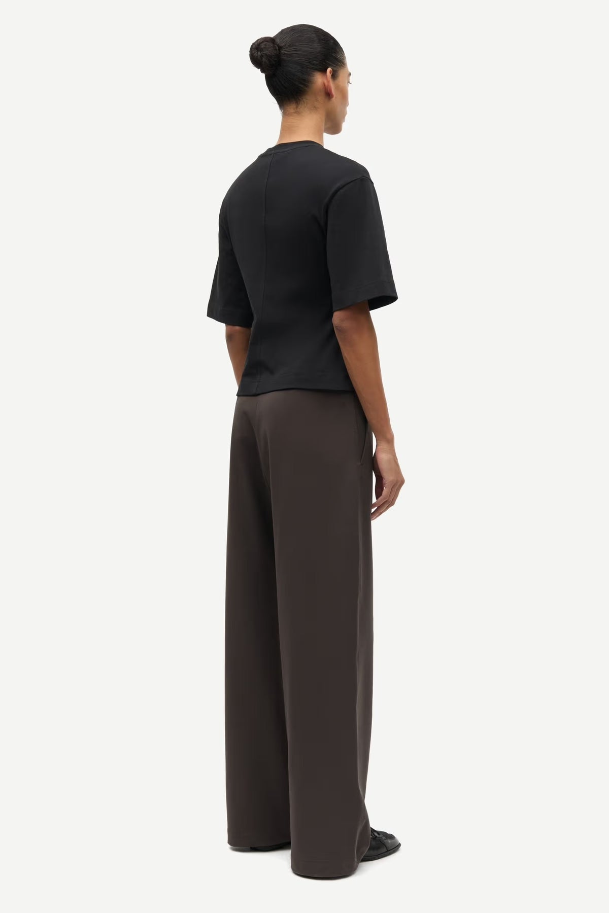 Person wearing a black top and dark pants on a white background
