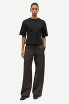 Person wearing a black t-shirt and brown pants on a white background