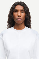 Person wearing a plain white shirt against a light background