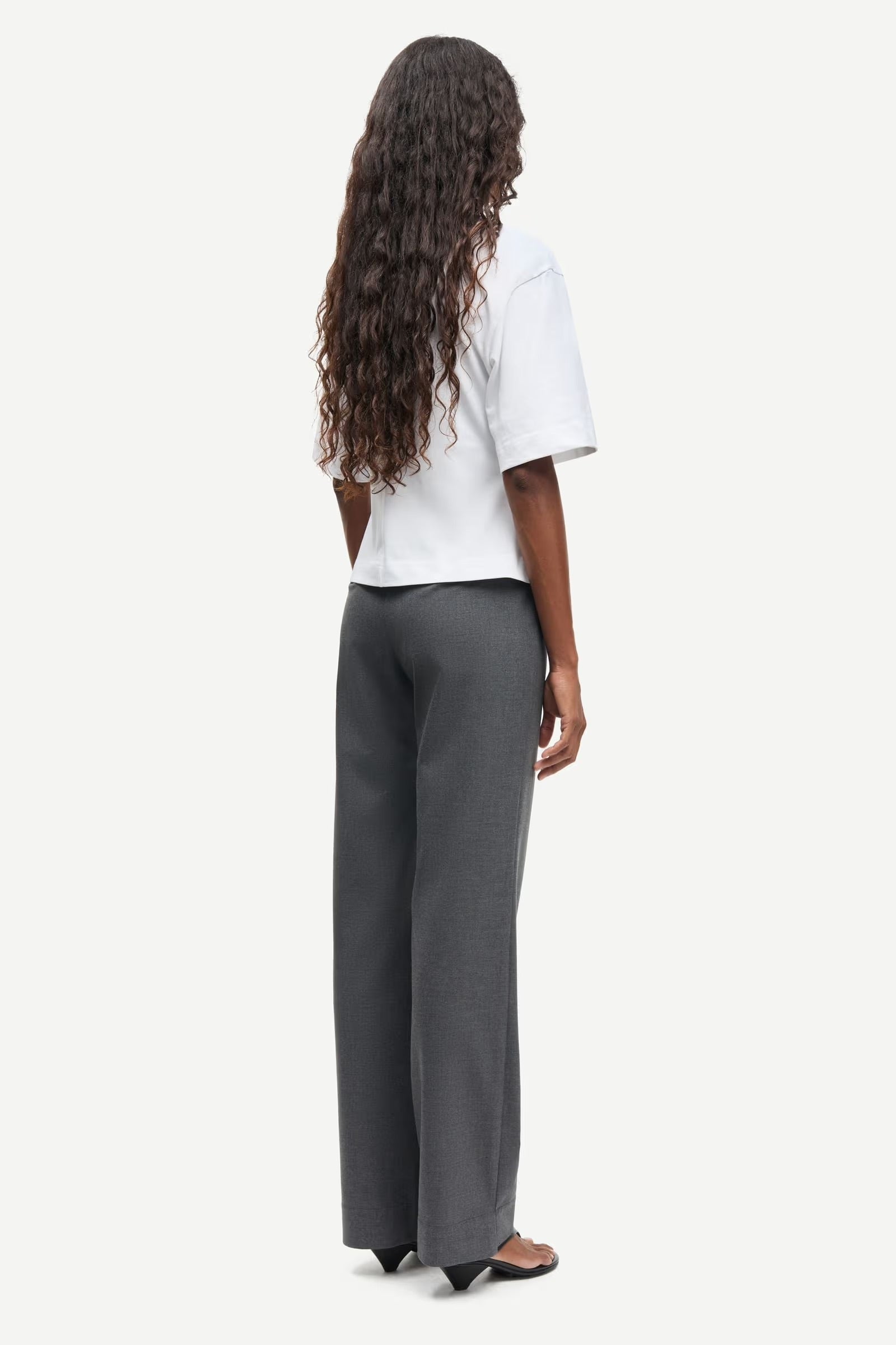 Person wearing a white top and gray pants on a white background