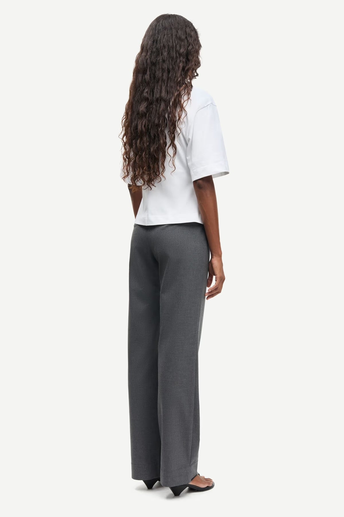 Person wearing a white top and gray pants on a white background