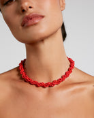 Red necklace worn by a model on a plain background