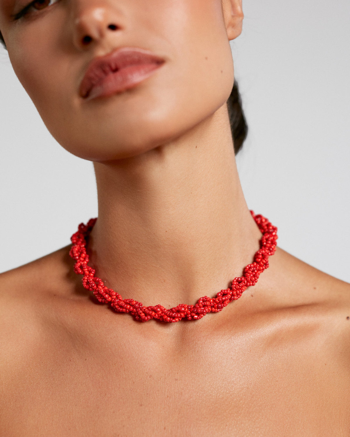 Red necklace worn by a model on a plain background