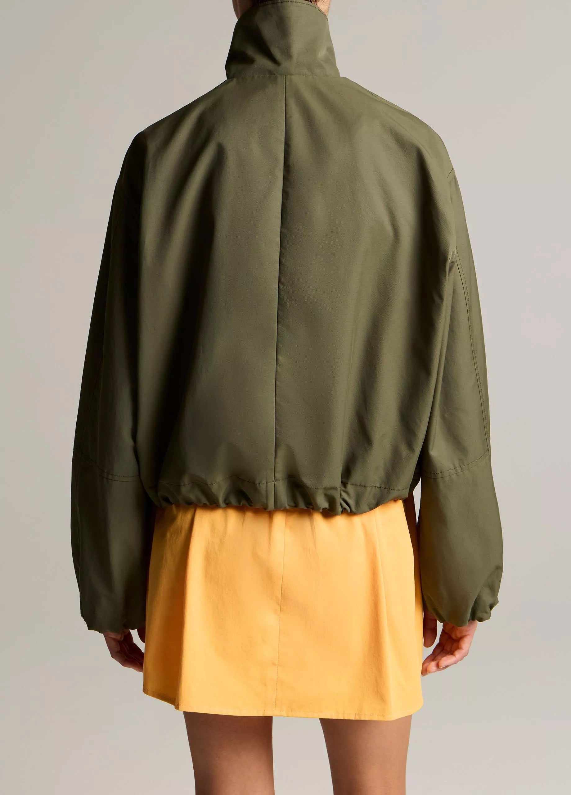 woman wears green jacket and yellow skirt
