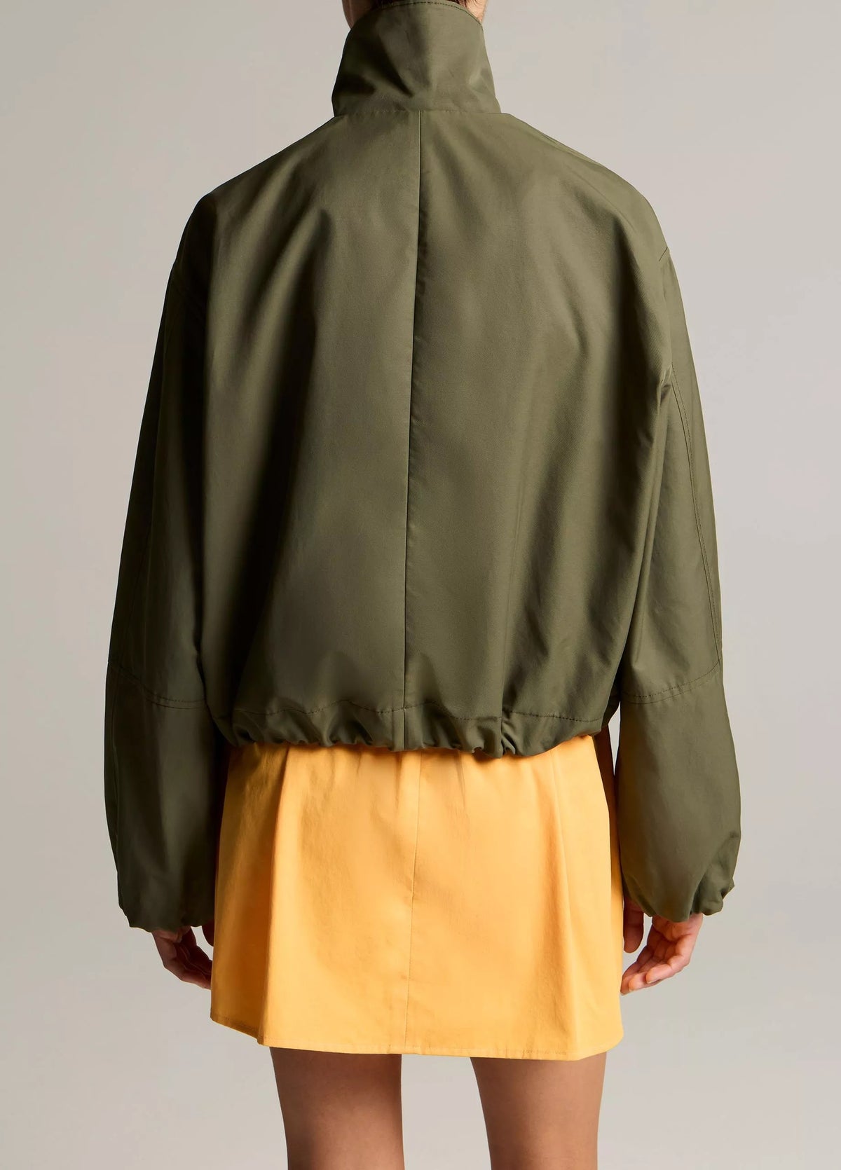 woman wears green jacket and yellow skirt